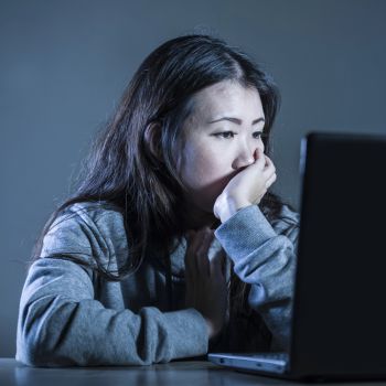 Young person using the computer screen excessively and looking sad and isolated.