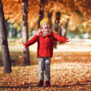 child delighted at autumn leaves